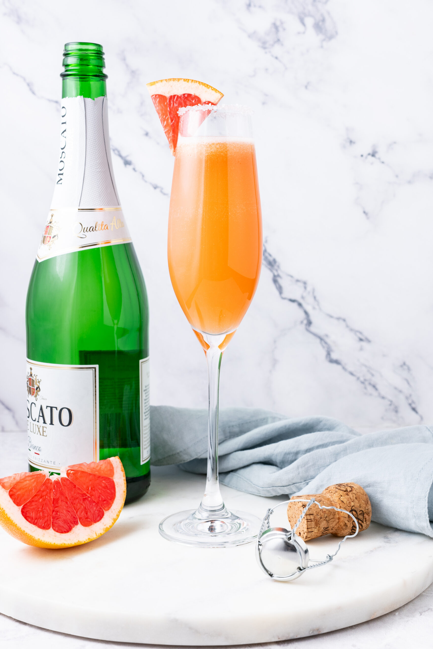 A Champagne Paloma cocktail in a flute glass, garnished with a grapefruit wedge.