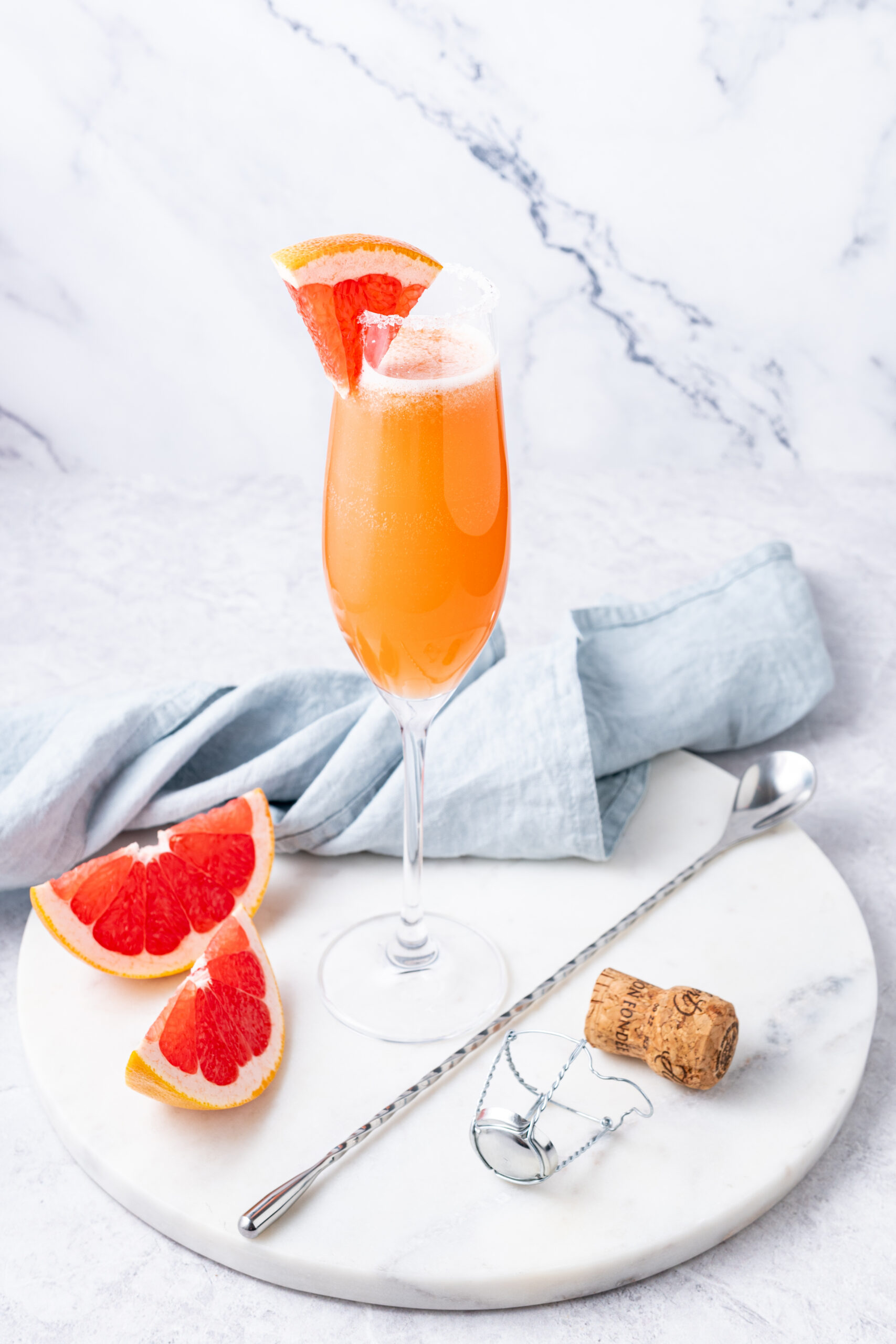 Champagne Paloma cocktail in a flute glass, garnished with a grapefruit wedge.