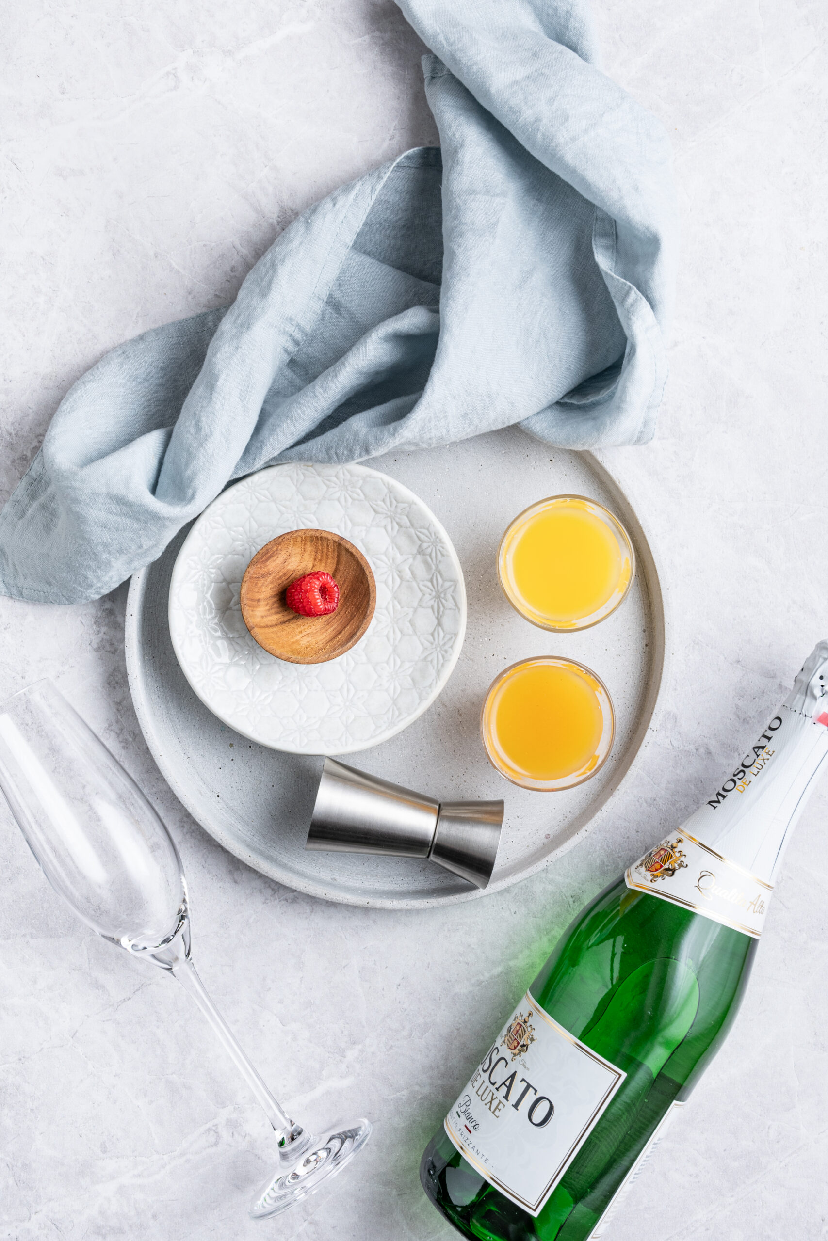 Peach Mimosa ingredients on a round tray - twistandtoast