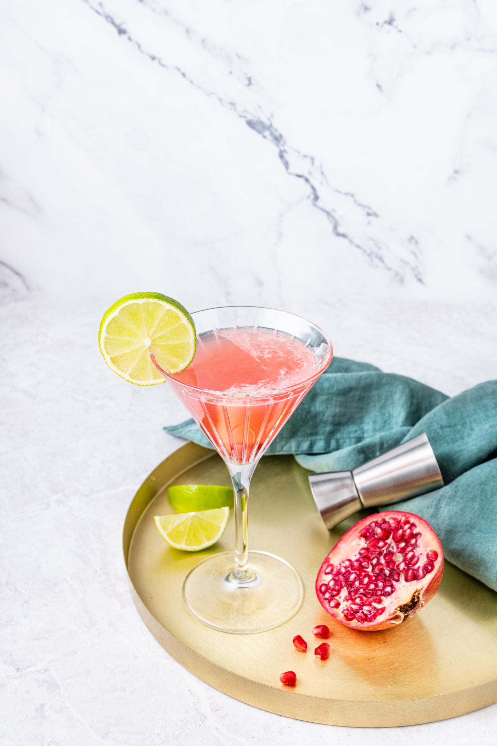Pomegranate Cosmopolitan in a cocktail glass on a tray diagonal shot