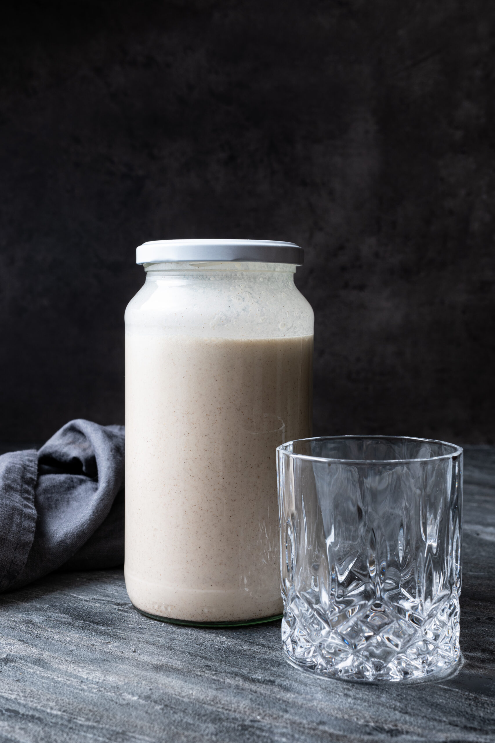 RumChata in glass bottle next to a glass shot from the side