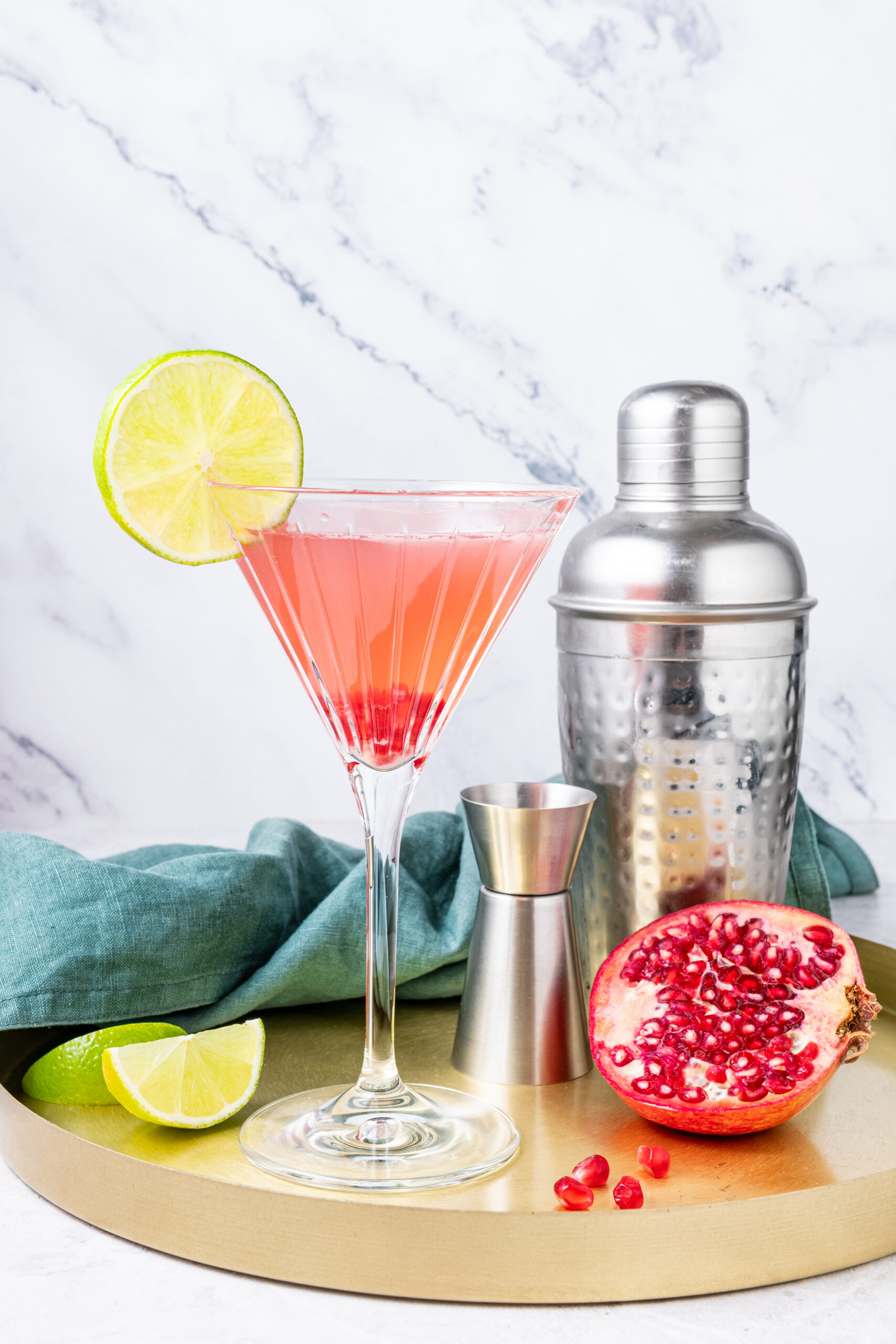 Pomegranate Cosmopolitan in a cocktail glass on a tray side shot